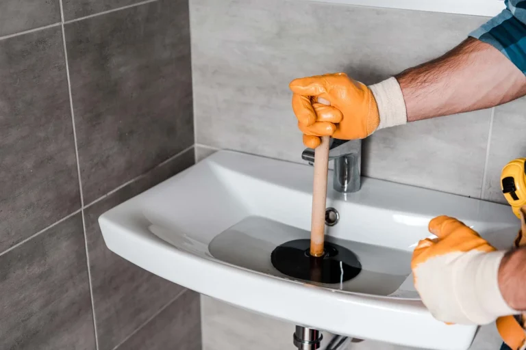 cropped-view-of-man-holding-plunger-in-sink-with-w